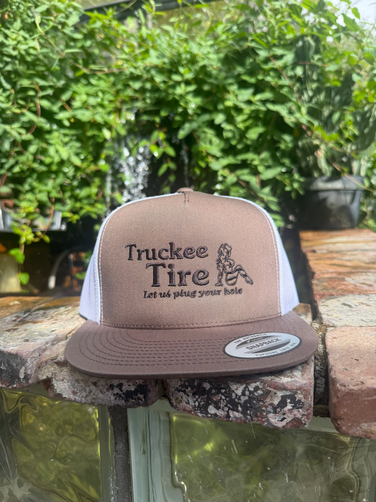 Brown and white Yupoong 6006 trucker hat with Truckee Tire logo embroidered in black
