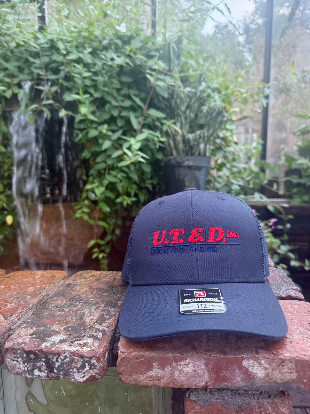 Navy Richardson 112 trucker hat with U.T.&D. Inc. Union Tool and Die logo embroidered in red and navy